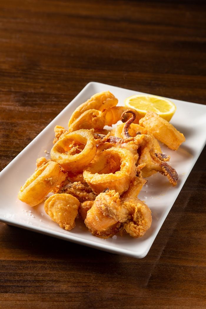 Calamares fritos a la andaluza, rebozados y dorados, servidos con un gajo de limón.